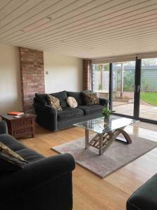 a living room with a black couch and a glass table at Meadow Barn in Hereford