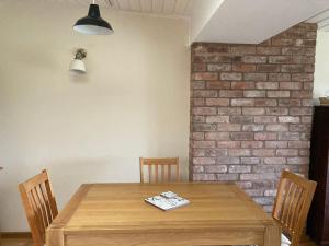 a wooden table with chairs and a brick wall at Meadow Barn in Hereford