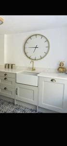 a clock on a wall above a white desk at Chelston Grange Torquay Near the Beach with Private Garden & Parking in Torquay