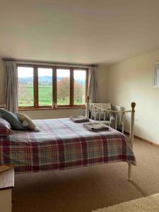 a bedroom with a bed with a plaid blanket and a window at Meadow Barn in Hereford
