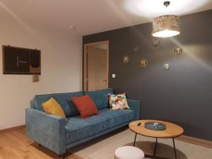 ein Wohnzimmer mit einem blauen Sofa und einem Tisch in der Unterkunft Le Cottage in Sorans-lès-Breurey