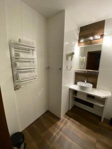 La salle de bains blanche est pourvue d'un lavabo et d'un miroir. dans l'établissement Hotel Constancja, à Częstochowa