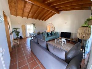 a living room with a blue couch and a tv at Arrifana Beach Break in Aljezur