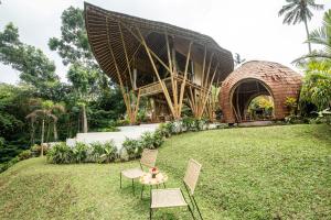 uma mesa e cadeiras na relva em frente a um edifício em Magic Hills Bali - Magical Eco-Luxury Lodge em Selat