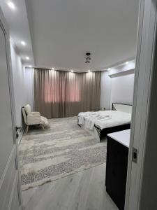 una camera da letto con un letto e una sedia in una stanza di Думан-2 a Almaty Altre 7 foto