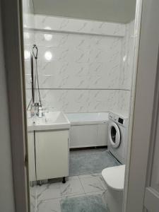 bagno con vasca, lavandino e lavatrice di Думан-2 a Almaty