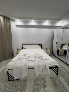 una camera da letto con un letto con lenzuola e specchi bianchi di Думан-2 a Almaty