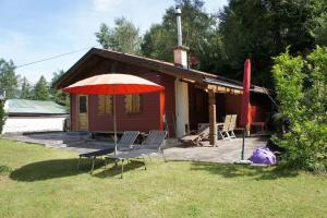 ein Haus mit Stühlen und einem Sonnenschirm davor in der Unterkunft Waldchalet Tulfes in Rinn