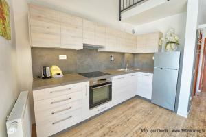 a kitchen with white cabinets and a refrigerator at Terme Olimia - Apartment 407 in Podčetrtek