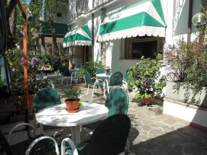 an outdoor patio with tables and chairs and a green umbrella at Camere Capinera in Cesenatico