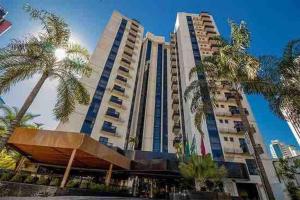 a large building with palm trees in front of it at Sun Square Marista Vista Pça do Sol! Hospitais,mercados e cartórios, tudo perto! 301 in Goiânia