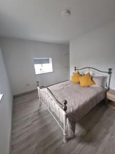 Un dormitorio con una cama con almohadas amarillas. en Welcome to DC's Cottage, en Holycross