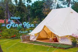 a tent is set up in the grass at Baan Pingkan Wellness Resort in San Kamphaeng