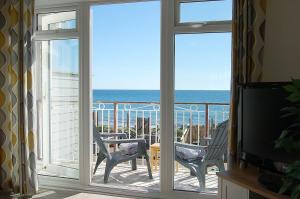 a room with a view of the ocean from a balcony at Sunny Side Up Beach House in Tywyn in Tywyn