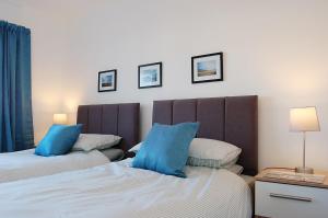 a bedroom with two beds with blue pillows at Sunny Side Up Beach House in Tywyn in Tywyn