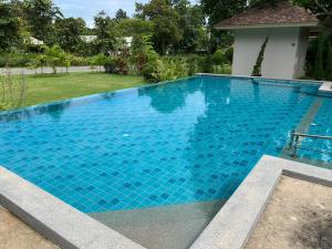 una gran piscina de agua azul en un patio en Baan Pingkan Wellness Resort, en San Kamphaeng