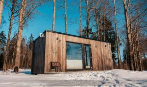 a small cabin with a chair in the snow at Juusa cabin in Otepää