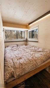 a bed in a small room with two windows at Juusa cabin in Otepää