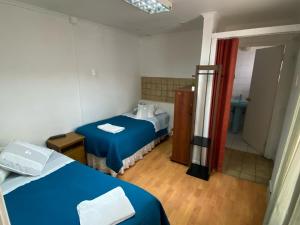 a small room with two beds and a bathroom at Karol Hostal in Punta Arenas