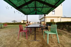 eine Gruppe von Stühlen um einen Tisch unter einem Schirm in der Unterkunft OYO Hotel Ishwar in Jaipur