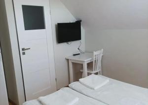 a bedroom with a bed and a small table and a television at Dom Lidia in Poddąbie