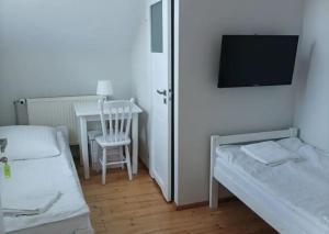 um quarto com duas camas e uma mesa e uma televisão em Dom Lidia em Poddabie