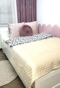 a bedroom with a bed with a pink and white comforter at APARTAMENT JARACZA 28/11 in Słupsk