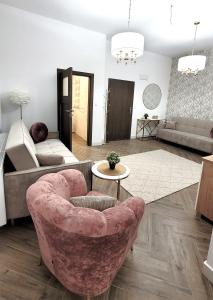 a living room with a pink chair and a couch at APARTAMENT JARACZA 28/11 in Słupsk