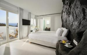 a white bedroom with a large bed and a balcony at Million Stars Mykonos in Mikonos