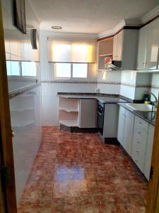 uma cozinha com armários brancos e piso em azulejo em Albufera Rooms em Valência