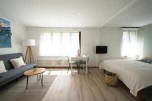 een slaapkamer met een bed, een bank en een tafel bij Bijou Studio with Ambiance near Lake in Faulensee