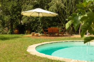 un tavolo e un ombrellone accanto alla piscina di ALFA COUNTRY HOUSE Villa Salento a Lequile