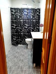 a bathroom with a black shower curtain and a toilet at Albufera Rooms in Valencia