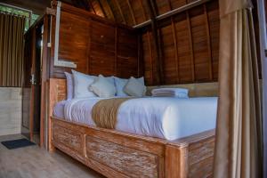 1 dormitorio con 1 cama grande y paredes de madera en Abing Dalem - Villa Mangga en Tabanan