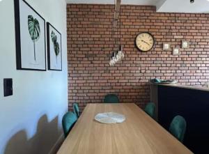 a room with a wooden table and a clock on a brick wall at Kolejowa 4 Boutique Apartment in Nowa Ruda