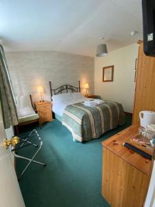 a bedroom with a bed and a table with a chair at Glenan Lodge Self Catering in Tomatin