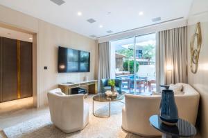 a living room with a couch and chairs and a television at GuestReady - Private Pool at the FIVE in Dubai