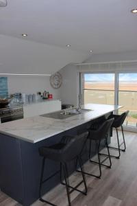 a kitchen with a counter with chairs and a sink at The Old Lifeboat Station of Hoylake in Hoylake