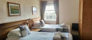 een hotelkamer met 2 bedden en een raam bij The Bell Hotel in Burgh le Marsh