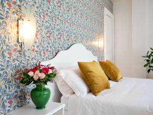 una camera da letto con un letto e un vaso di fiori su un tavolo di Relais San Martino Salento - Handwritten Collection a Taviano
