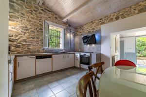 a kitchen with white cabinets and a stone wall at Mazet Pierre de Vers - Le Mas des Olivers Nîmes in Nîmes