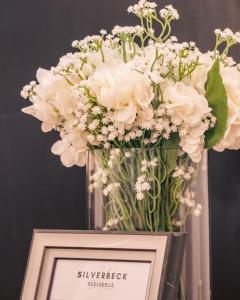 a vase filled with white flowers on top of a picture at Silverbeck Residence, Nanyuki in Nanyuki