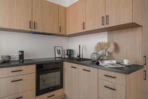 a kitchen with wooden cabinets and a black counter top at HARBOR APARTMENTS - Mickiewicza in Katowice