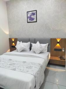 a bedroom with a large bed with white sheets at Hotel Paris inn in Ahmedabad