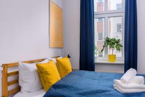 ein Schlafzimmer mit einem Bett mit gelben Kissen und einem Fenster in der Unterkunft Plac Grunwaldzki Cosy Apartment in Breslau