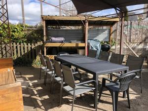 einem schwarzen Tisch mit Stühlen und einem Sonnenschirm in der Unterkunft La Maison de Suzanne in Murol