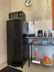 una nevera negra en una cocina con estantería en Suítes classic, en Búzios