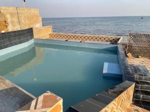 a swimming pool with the ocean in the background at Rayyan Beach House in Karachi