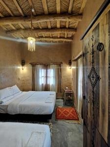 1 Schlafzimmer mit 2 Betten und einem Kronleuchter in der Unterkunft Maison d'hôte tamatart - Homestay in El-Kelâa M’Gouna
