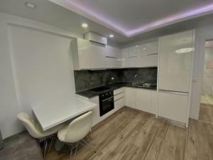 cocina con armarios blancos y techo púrpura en Central Apartment Blloku, en Tirana